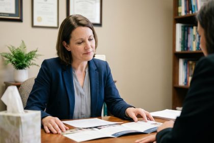 Conseillère en pompes funèbres accompagnant une famille en deuil lors d'un entretien dans un bureau professionnel et chaleureux